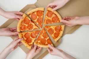 Hands grabbing pepperoni pizza