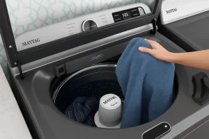 Hand loading towel into top load washers with agitators.