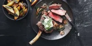 Best Steak Delivery bone-in ribeye steak with sides on dark plate