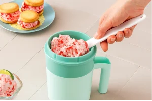 Scooping strawberry ice cream from mug